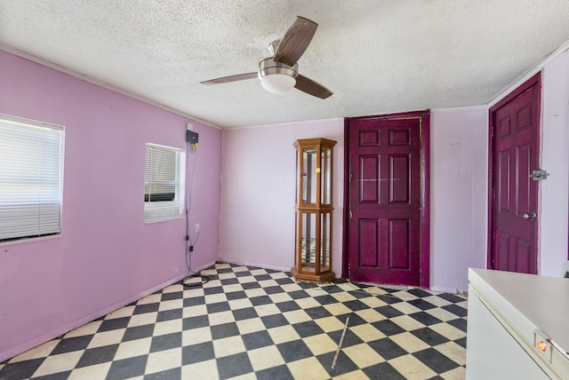 entrance foyer with ceiling fan, a textured ceiling, and wooden walls