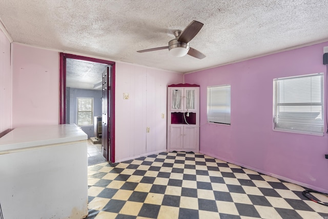 unfurnished room with ceiling fan and a textured ceiling