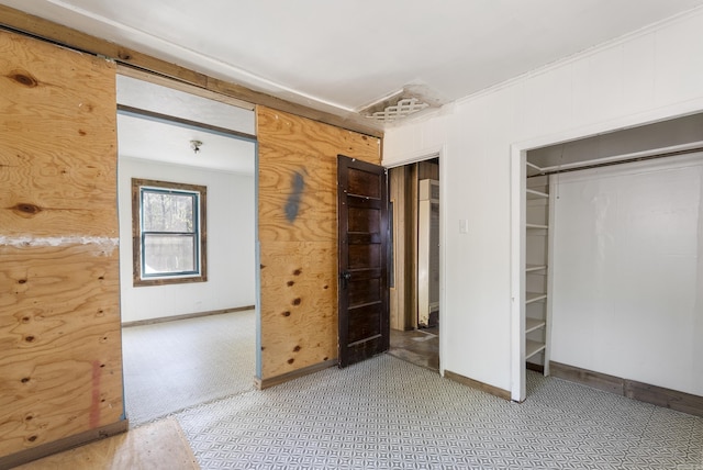 unfurnished bedroom with a closet and wood walls