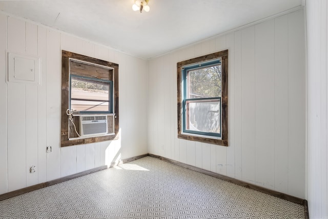 spare room with wood walls, plenty of natural light, and cooling unit