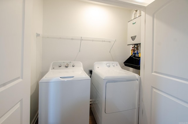 clothes washing area featuring water heater and separate washer and dryer