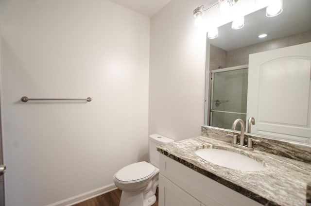 bathroom with toilet, hardwood / wood-style flooring, walk in shower, and vanity