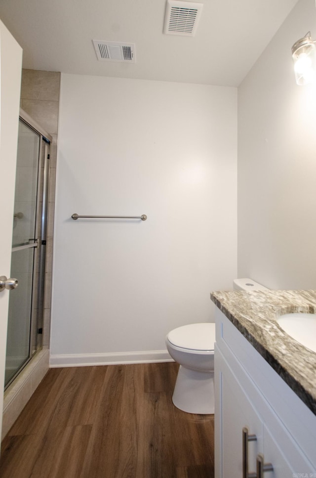 bathroom featuring a shower with door, toilet, vanity, and wood-type flooring