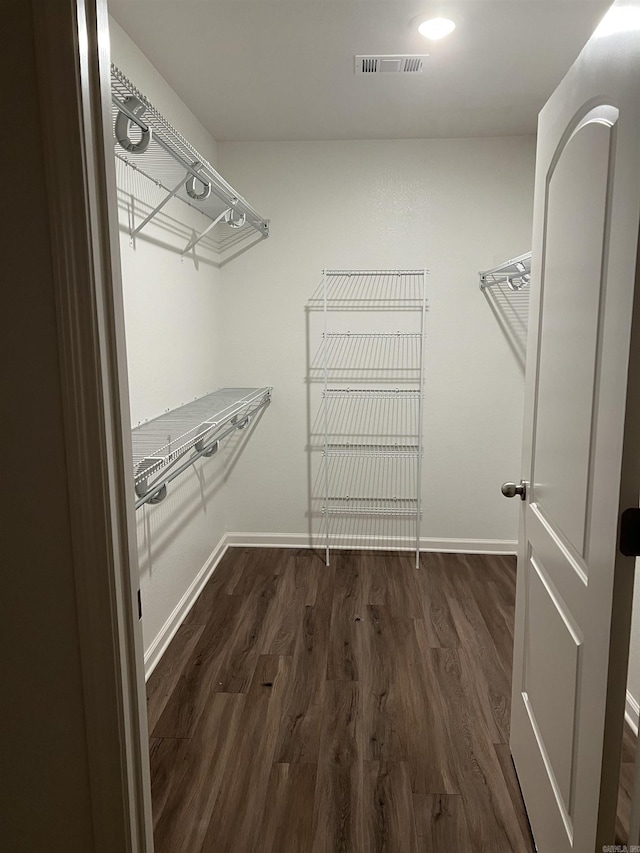 walk in closet with dark wood-type flooring