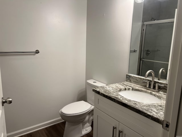 bathroom with hardwood / wood-style flooring, vanity, a shower with shower door, and toilet