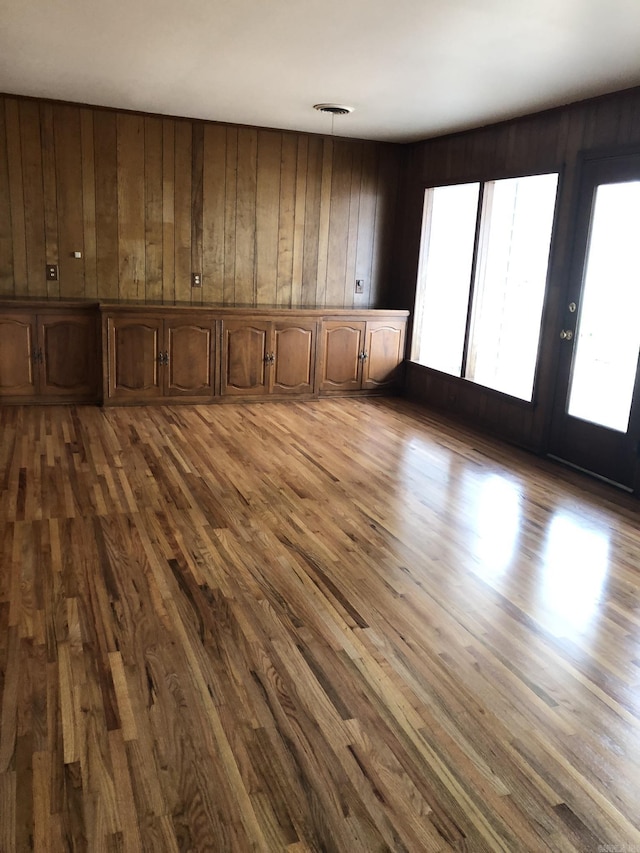 empty room with hardwood / wood-style floors, wooden walls, and french doors