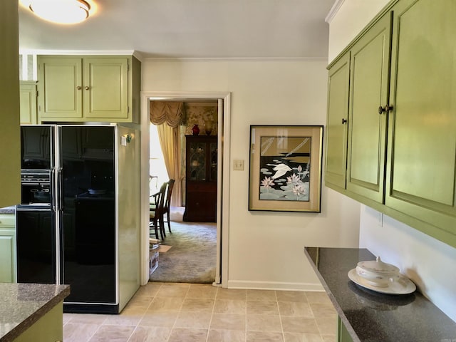 kitchen with black fridge, ornamental molding, dark stone countertops, and green cabinetry