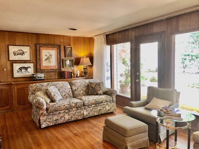 living room with hardwood / wood-style flooring, plenty of natural light, and wood walls