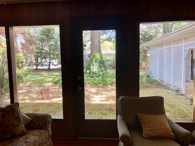 doorway to outside with wooden walls and a healthy amount of sunlight