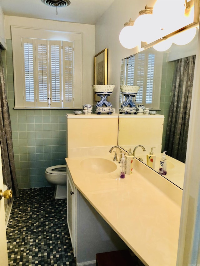 bathroom featuring plenty of natural light, toilet, tile walls, and vanity