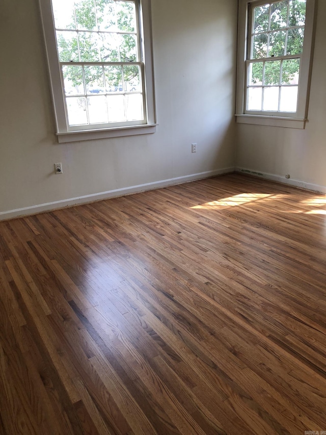 unfurnished room featuring plenty of natural light and dark hardwood / wood-style floors