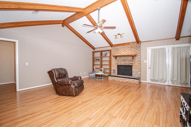 living room featuring ceiling fan, a fireplace, lofted ceiling with beams, and light wood-type flooring