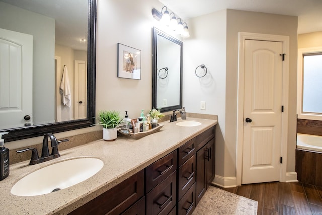 bathroom with wood-type flooring, vanity, and a bath