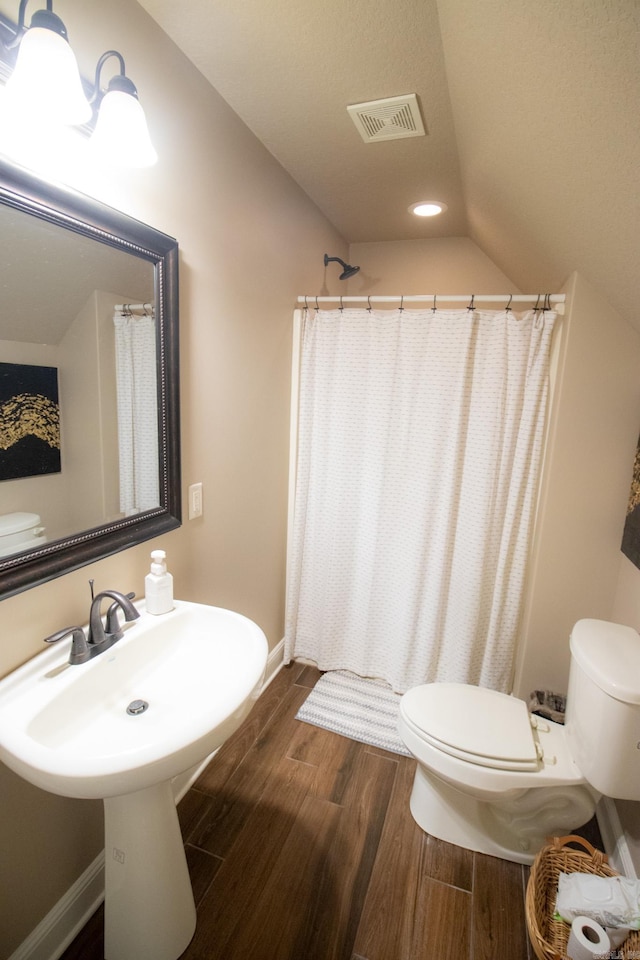 bathroom featuring wood-type flooring, toilet, lofted ceiling, and a shower with curtain