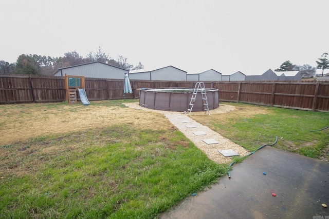 view of yard featuring a fenced in pool and a playground