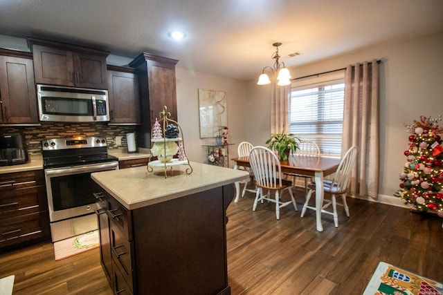 kitchen featuring stainless steel appliances, tasteful backsplash, decorative light fixtures, dark brown cabinets, and a kitchen island