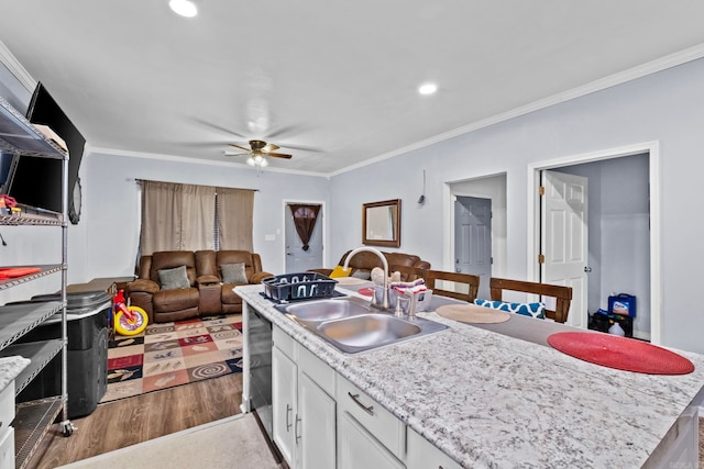 kitchen with sink, white cabinets, crown molding, an island with sink, and carpet