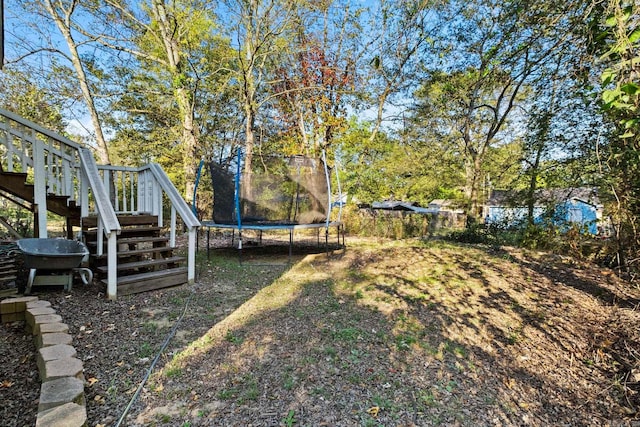 view of yard with a trampoline and a wooden deck