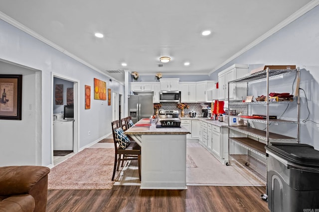 kitchen featuring appliances with stainless steel finishes, a center island, dark hardwood / wood-style flooring, and ornamental molding