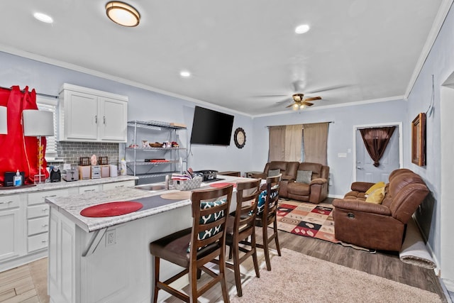 kitchen with light hardwood / wood-style floors, white cabinetry, and a kitchen island with sink