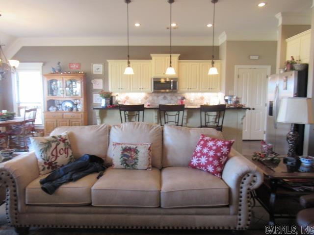 living room with crown molding and an inviting chandelier