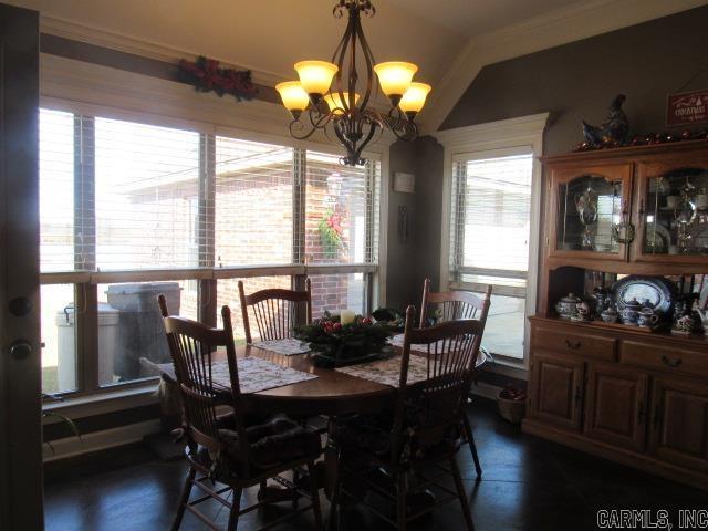 dining area with a notable chandelier, dark hardwood / wood-style flooring, and vaulted ceiling