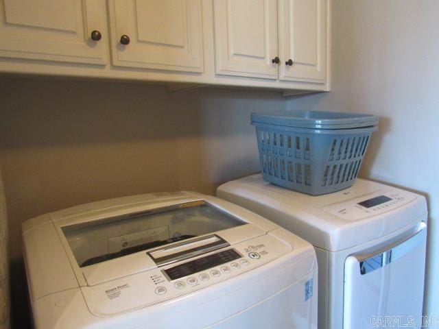 laundry room with washing machine and clothes dryer and cabinets