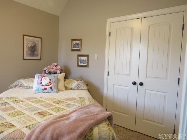 carpeted bedroom featuring a closet and lofted ceiling