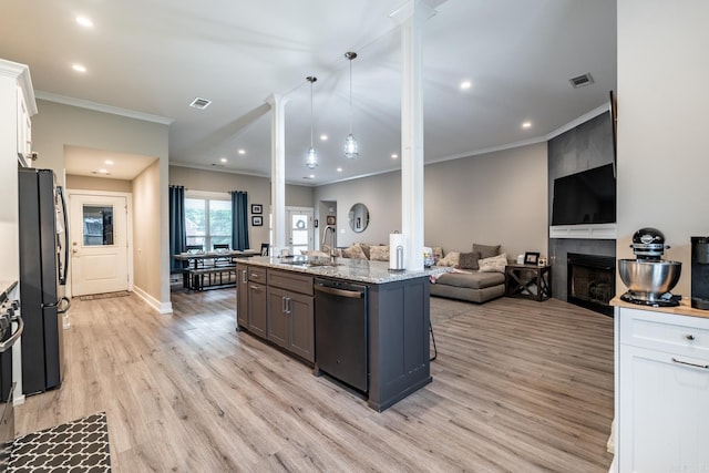 kitchen with black fridge, stainless steel dishwasher, a center island with sink, a fireplace, and white cabinetry