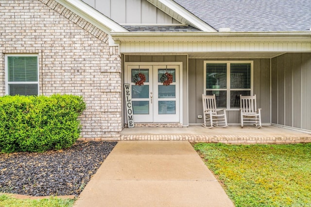 view of exterior entry featuring french doors and a porch