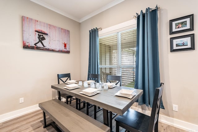 dining space with crown molding and light hardwood / wood-style flooring