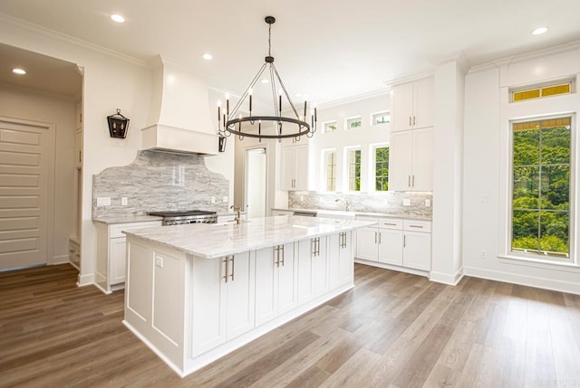 kitchen featuring premium range hood, white cabinetry, and a kitchen island with sink