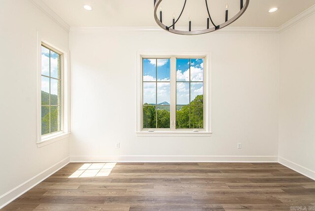 unfurnished dining area with wood-type flooring, ornamental molding, and a chandelier