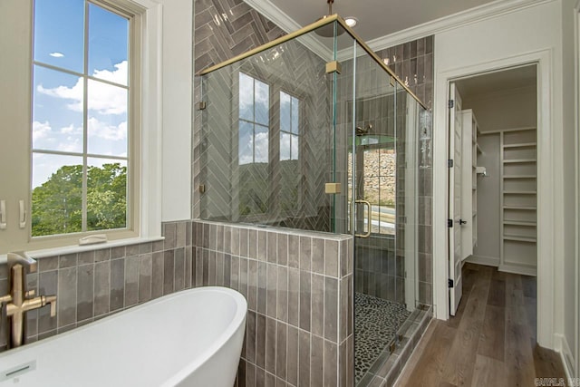 bathroom with hardwood / wood-style flooring, shower with separate bathtub, crown molding, and tile walls