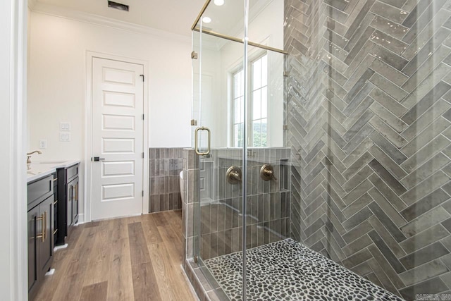 bathroom featuring ornamental molding, vanity, tile walls, hardwood / wood-style floors, and a shower with shower door