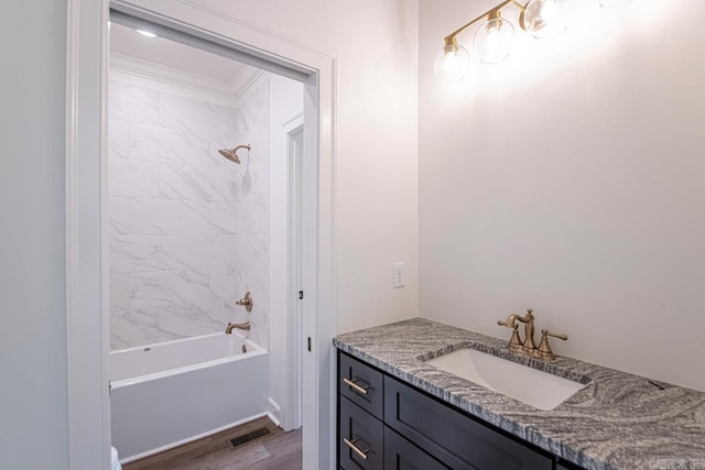 bathroom with crown molding, vanity, wood-type flooring, and tiled shower / bath