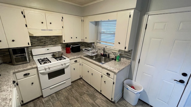 kitchen featuring white range with gas stovetop, tasteful backsplash, white cabinetry, and sink