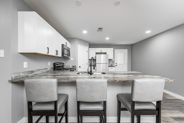 kitchen with kitchen peninsula, white cabinetry, sink, and stainless steel appliances