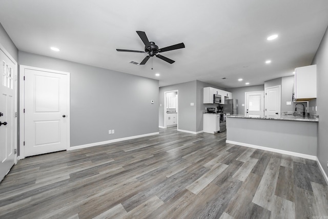 unfurnished living room featuring wood-type flooring, ceiling fan, and sink