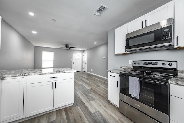 kitchen featuring appliances with stainless steel finishes, light wood-type flooring, light stone counters, ceiling fan, and white cabinets