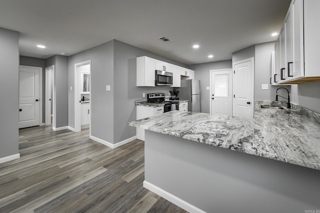 kitchen featuring white cabinetry, sink, dark hardwood / wood-style flooring, kitchen peninsula, and appliances with stainless steel finishes