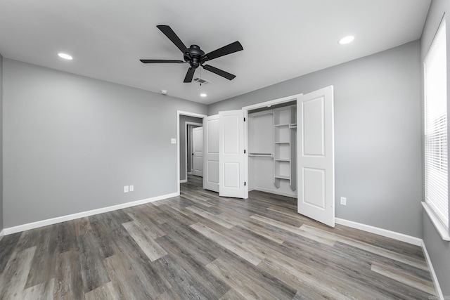 unfurnished bedroom featuring ceiling fan, a closet, and hardwood / wood-style flooring