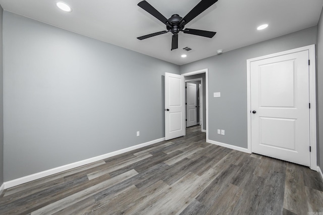 unfurnished bedroom with ceiling fan and dark wood-type flooring