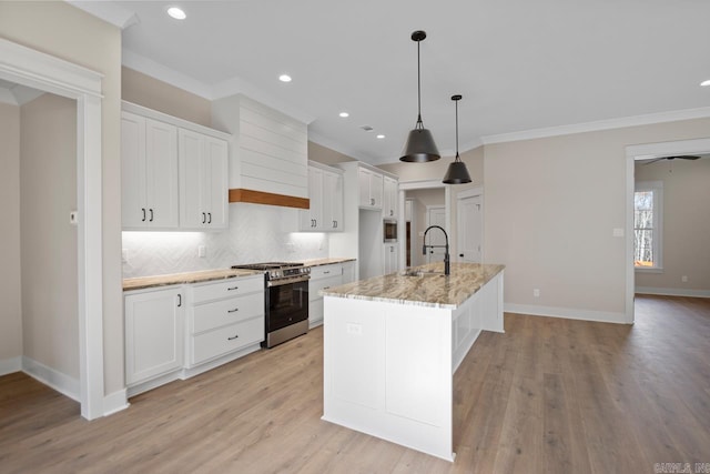 kitchen featuring a center island with sink, white cabinets, hanging light fixtures, light hardwood / wood-style floors, and gas stove