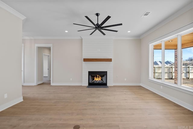 unfurnished living room featuring ceiling fan, crown molding, light wood-type flooring, and a fireplace