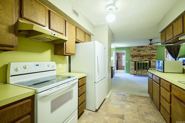 kitchen featuring plenty of natural light, white appliances, light carpet, and a brick fireplace