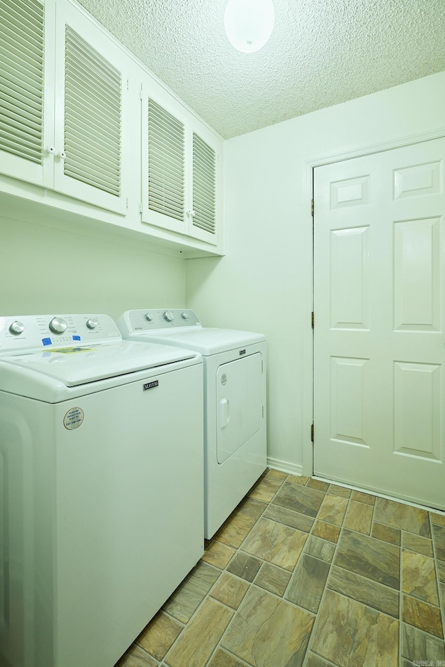 washroom with cabinets, a textured ceiling, and separate washer and dryer