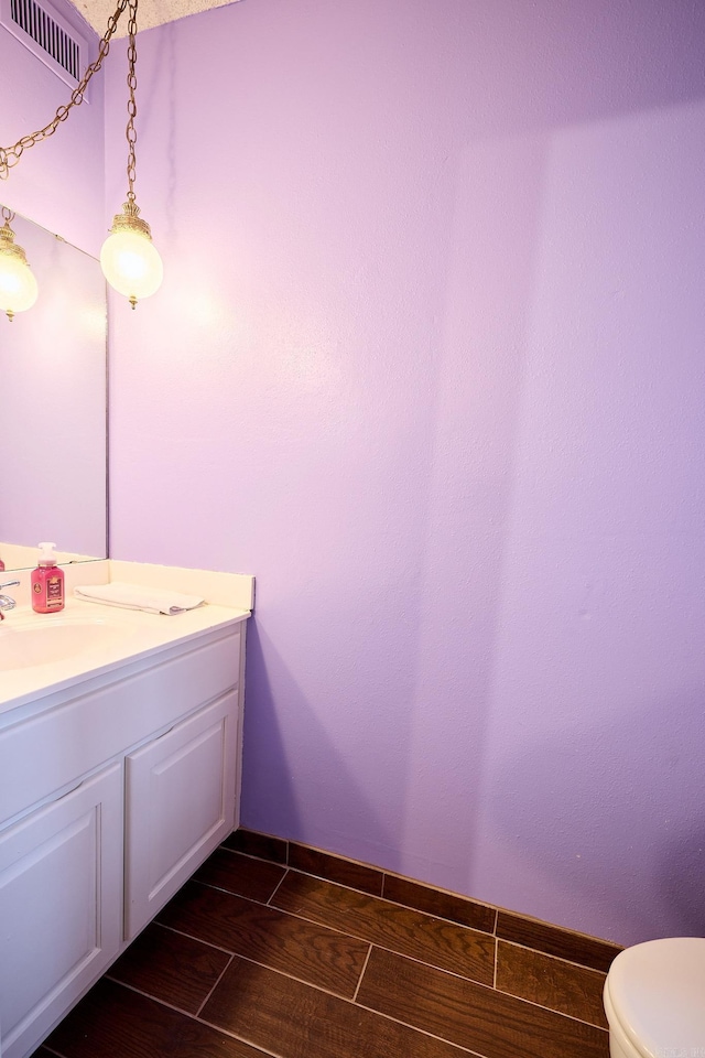 bathroom featuring vanity, wood-type flooring, and toilet