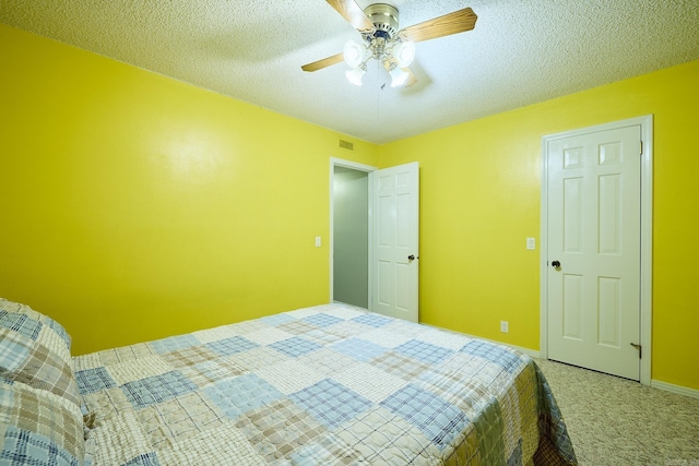 bedroom with ceiling fan, carpet floors, and a textured ceiling