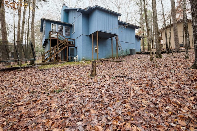 back of house featuring central AC unit and a trampoline